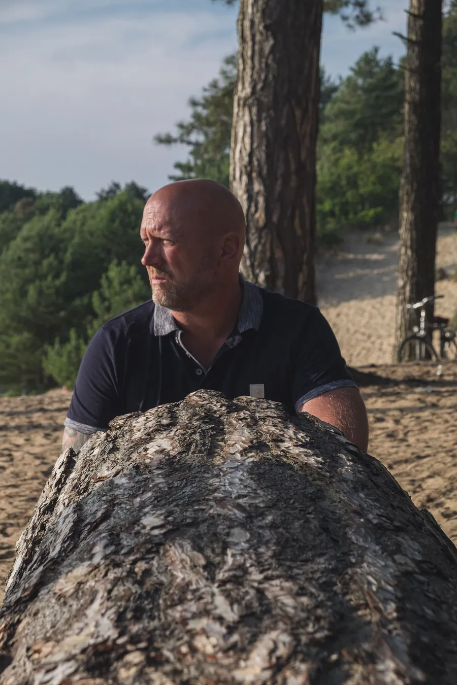 Patrick Scholten in de natuur, leunend op een boomstam