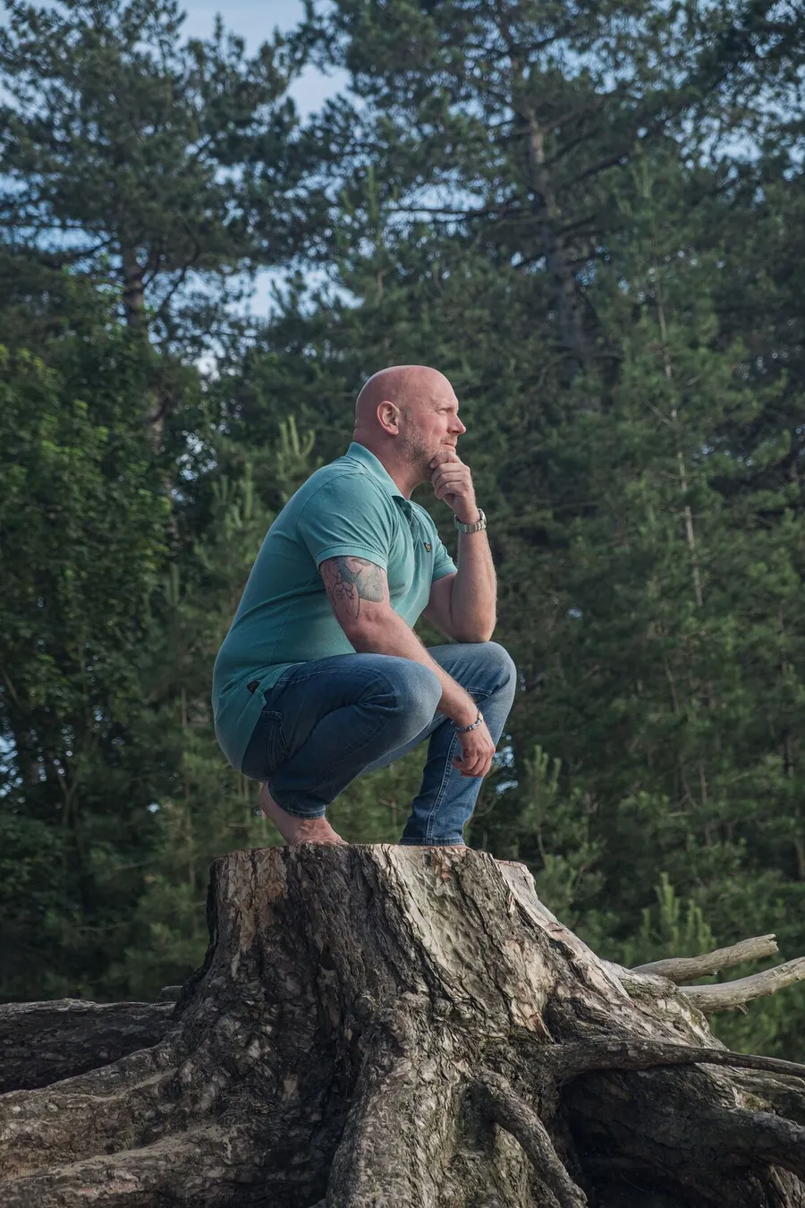 Patrick zit gehurkt op een boomstronk in het bos