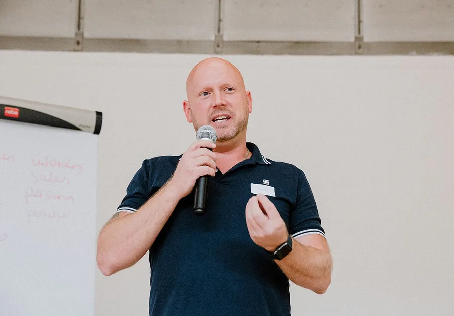 Patrick spreekt met microfoon tijdens een zaalsessie