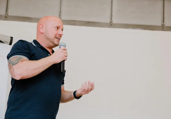 Patrick vertelt met microfoon in de hand tijdens een zaalsessie